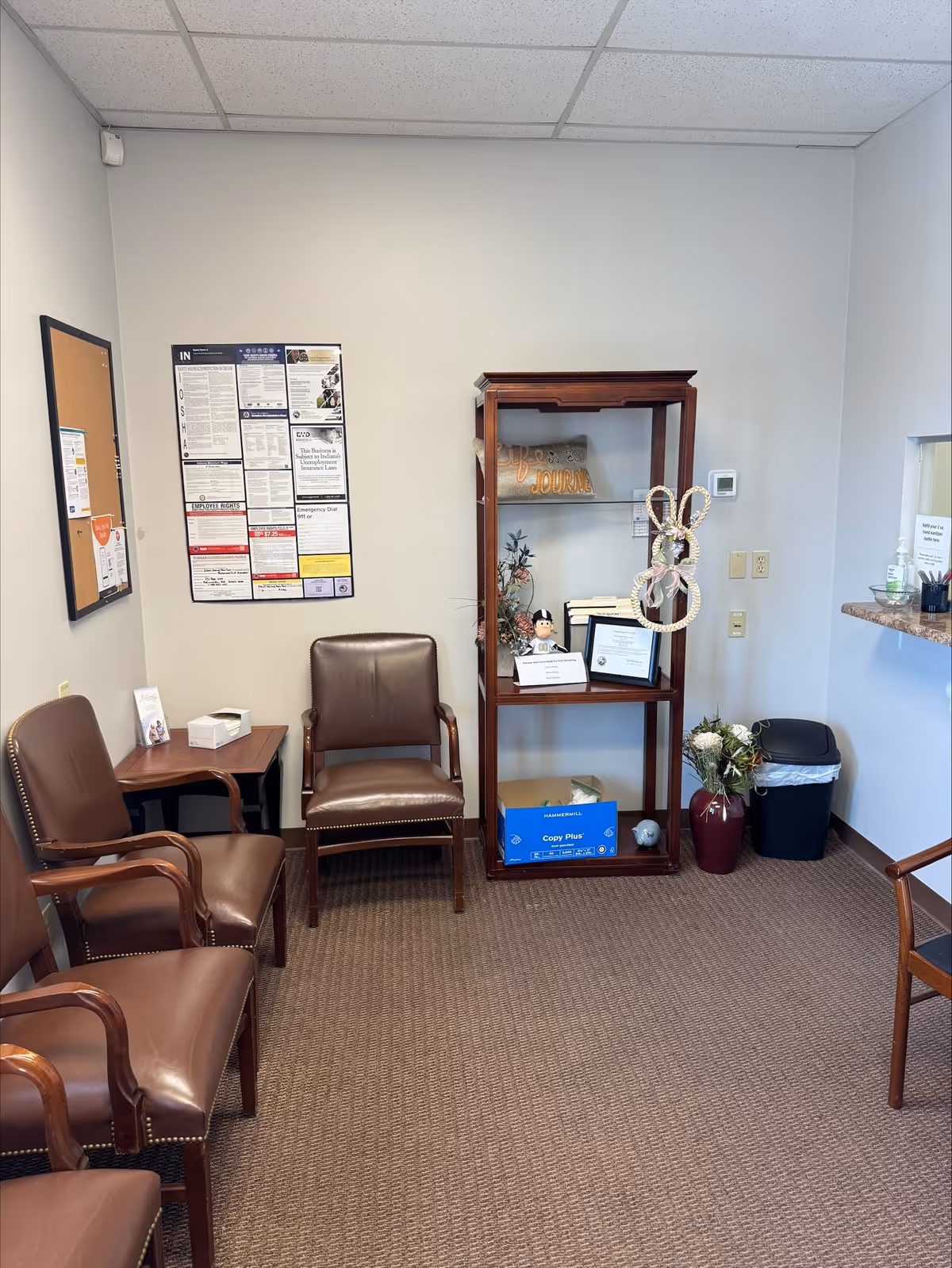 Waiting area in a senior care facility with brown chairs and bulletin boards.