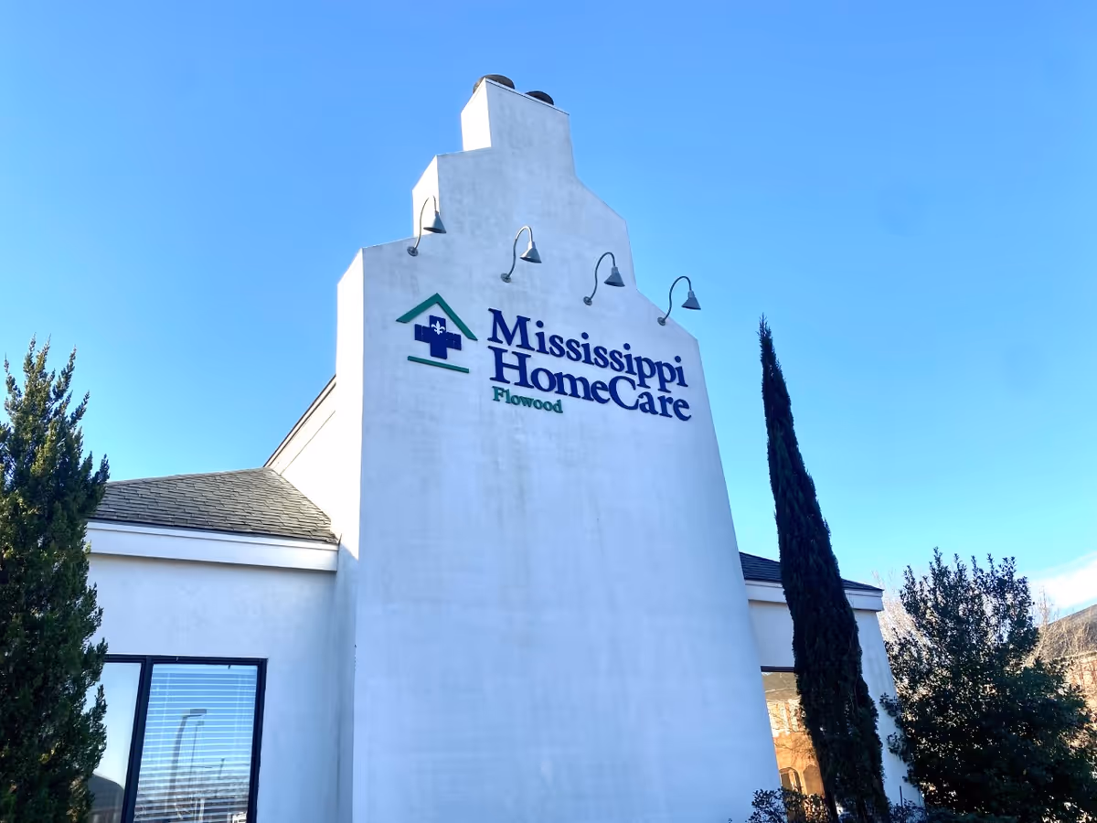 White exterior of Mississippi HomeCare Flowood building with its sign against a blue sky.