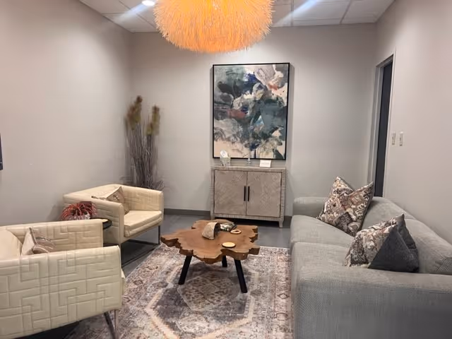 Modern living room lounge with gray sofas, chairs, a wooden coffee table, and abstract art.