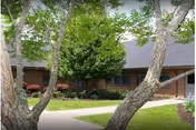 Exterior of Kempsville Health and Rehab Center with brick facade, trees, and a walkway.