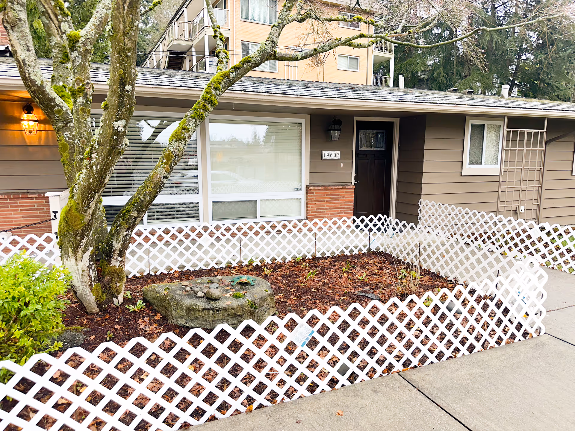 Front view of a single-story home with a white lattice fence.