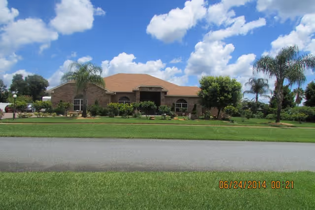 Exterior view of Summerhaven Assisted Living building with landscaped front and palm trees.