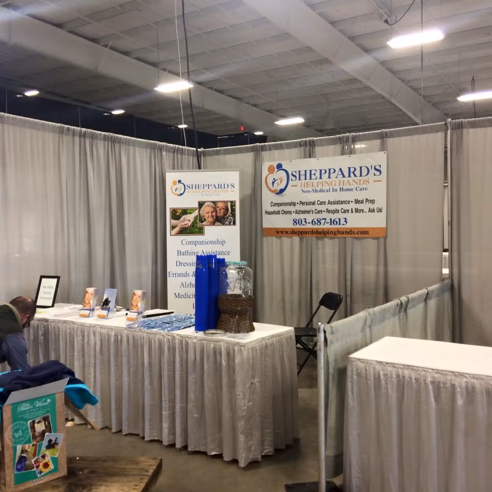 Indoor trade show booth for Sheppard's Helping Hands with banners and tables.