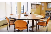 A round table with orange chairs in a sunlit dining room