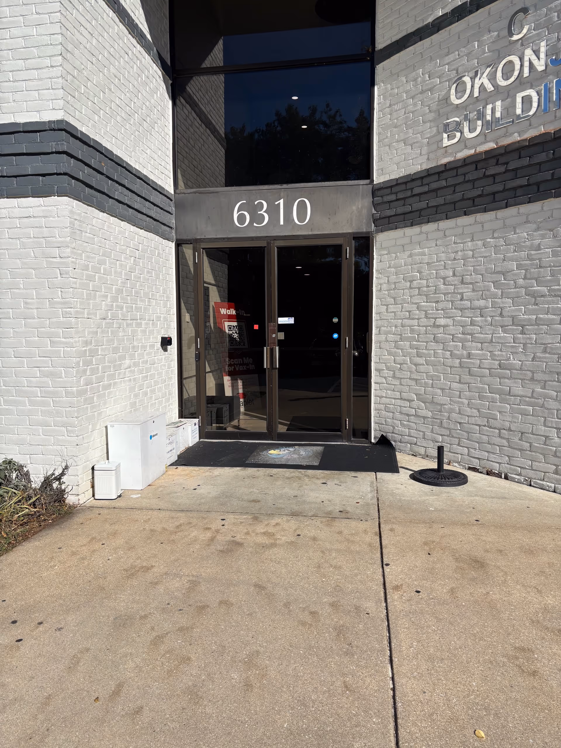 Front entrance of a brick building with large glass doors and the number 6310.