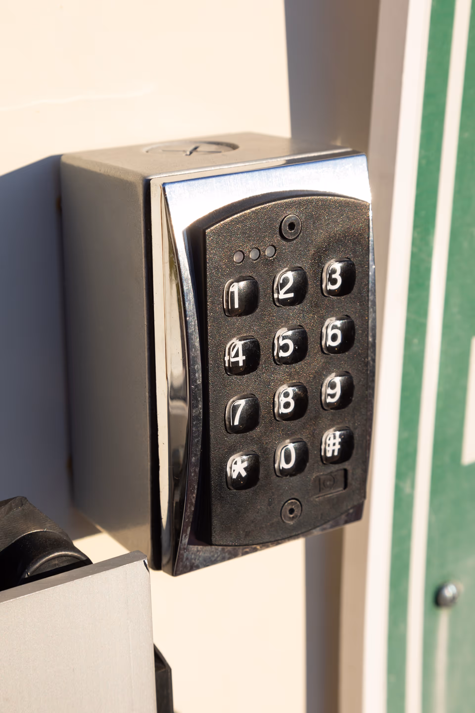 Close up of a keypad lock on an exterior door near a green framed entrance.