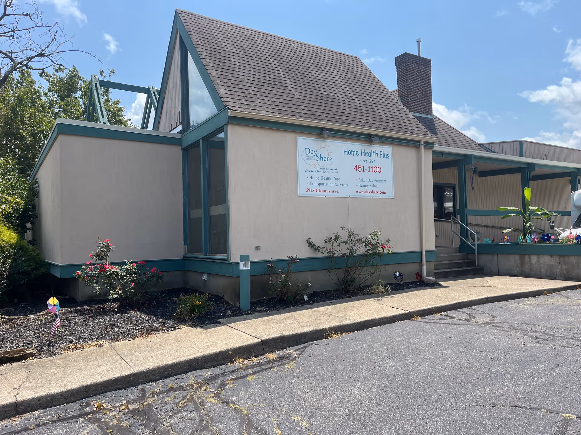 A single-story senior care center with a sign, entrance steps, and garden along the front.