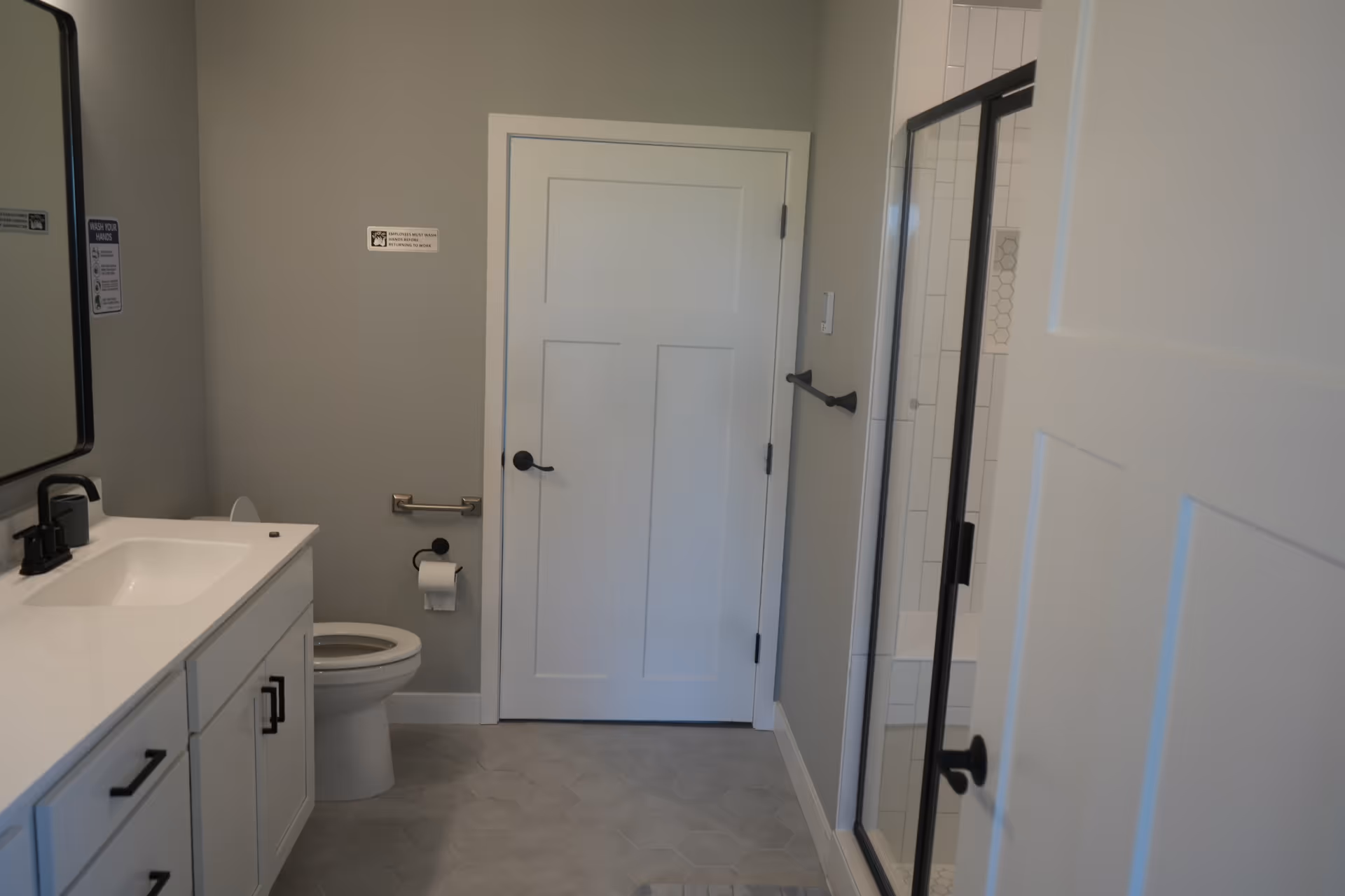 Modern bathroom with white vanity, toilet, and glass-enclosed shower.