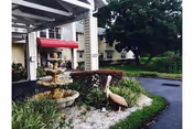 Front entrance of Bayou Gardens Assisted Living featuring a fountain and landscaped garden.