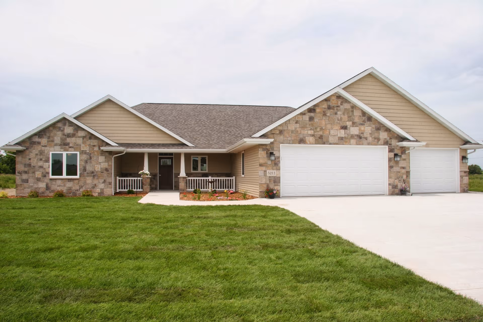 Single-story facility exterior with stone accents, three white garage doors, and a manicured front lawn.
