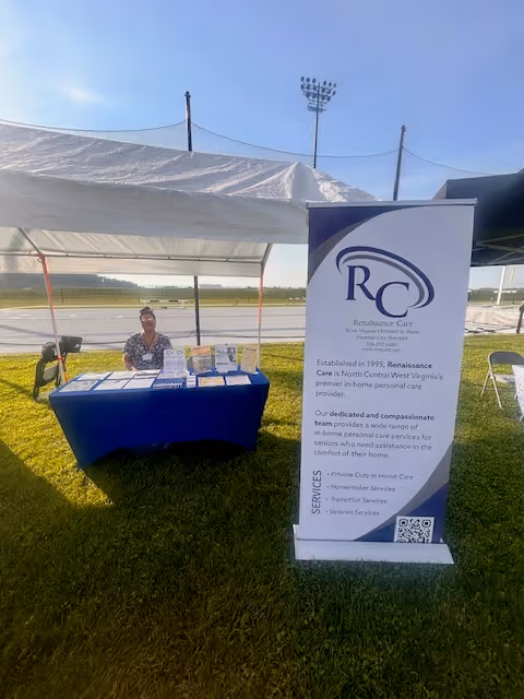 Outdoor Renaissance Care booth under a tent with a banner and table.