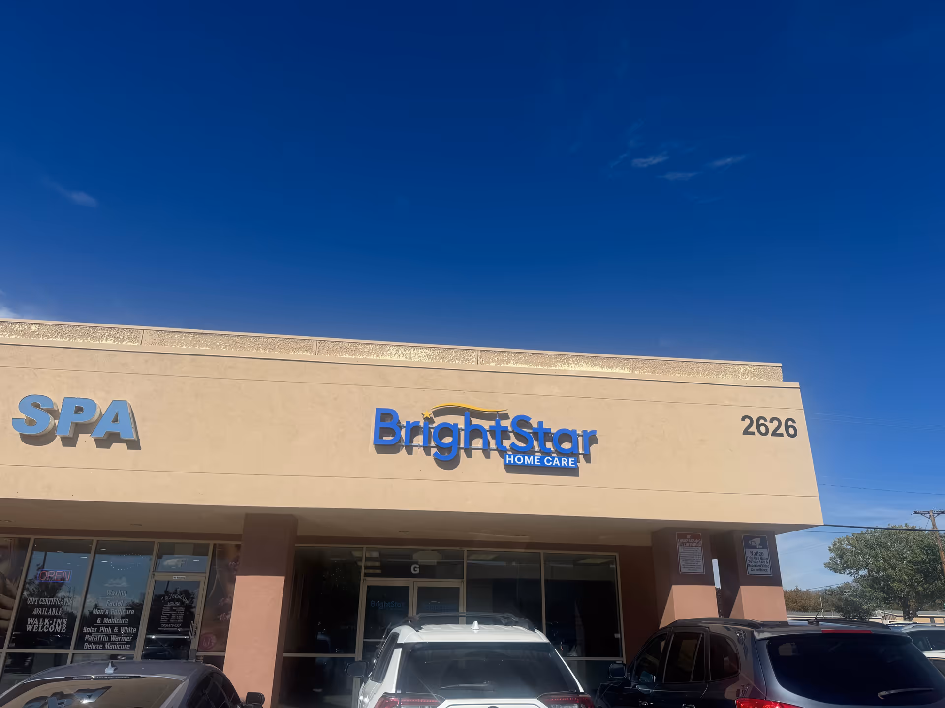 Exterior view of BrightStar Home Care storefront with blue sign and parked cars.