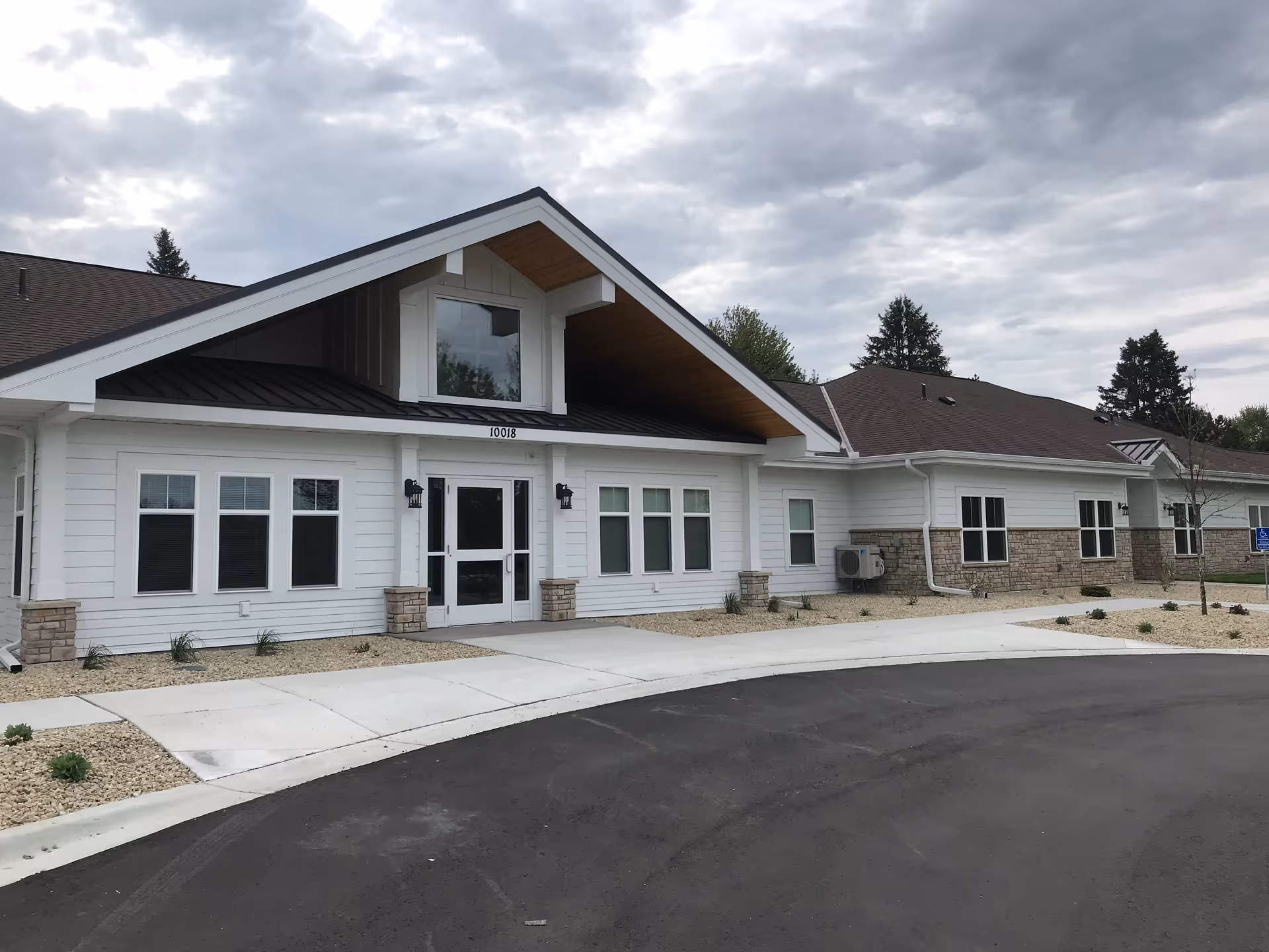 White single-story building with large entrance, gabled roof, and landscaped front yard.