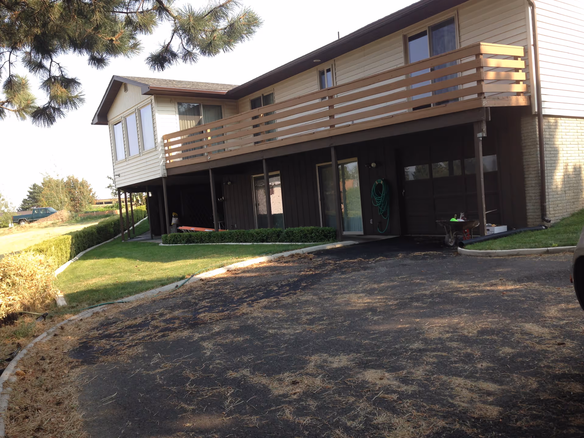Exterior view of a two-story senior living home with a wooden balcony and driveway.