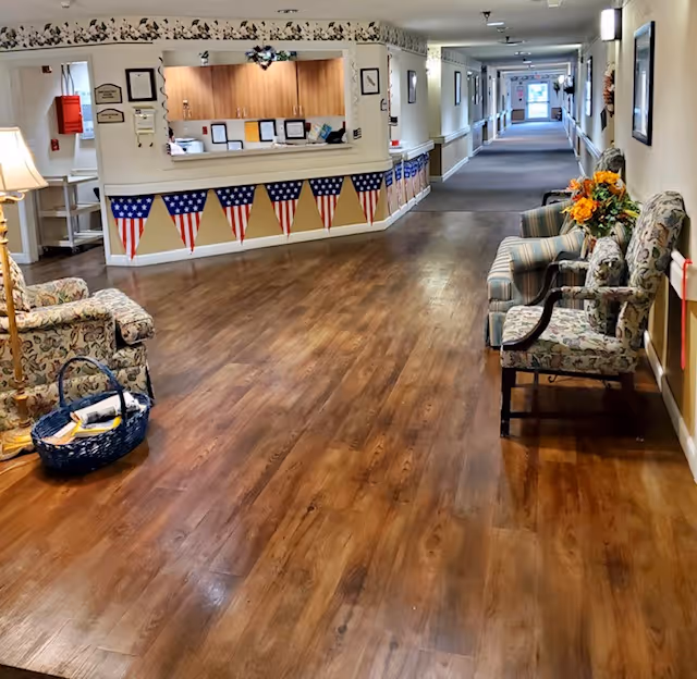 Patriotic bunting decorates the reception area along a wood-floored senior living hallway.