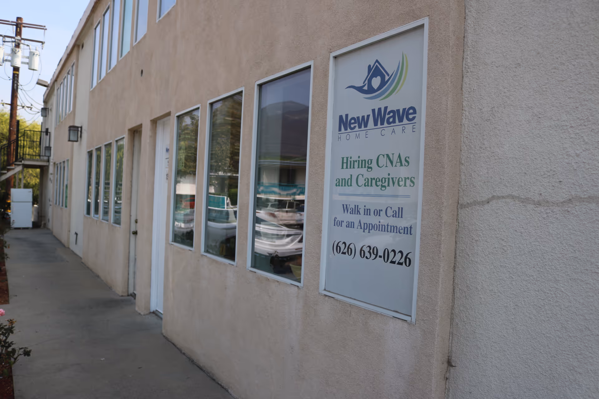 Exterior view of New Wave Home Care building with recruitment sign in window.