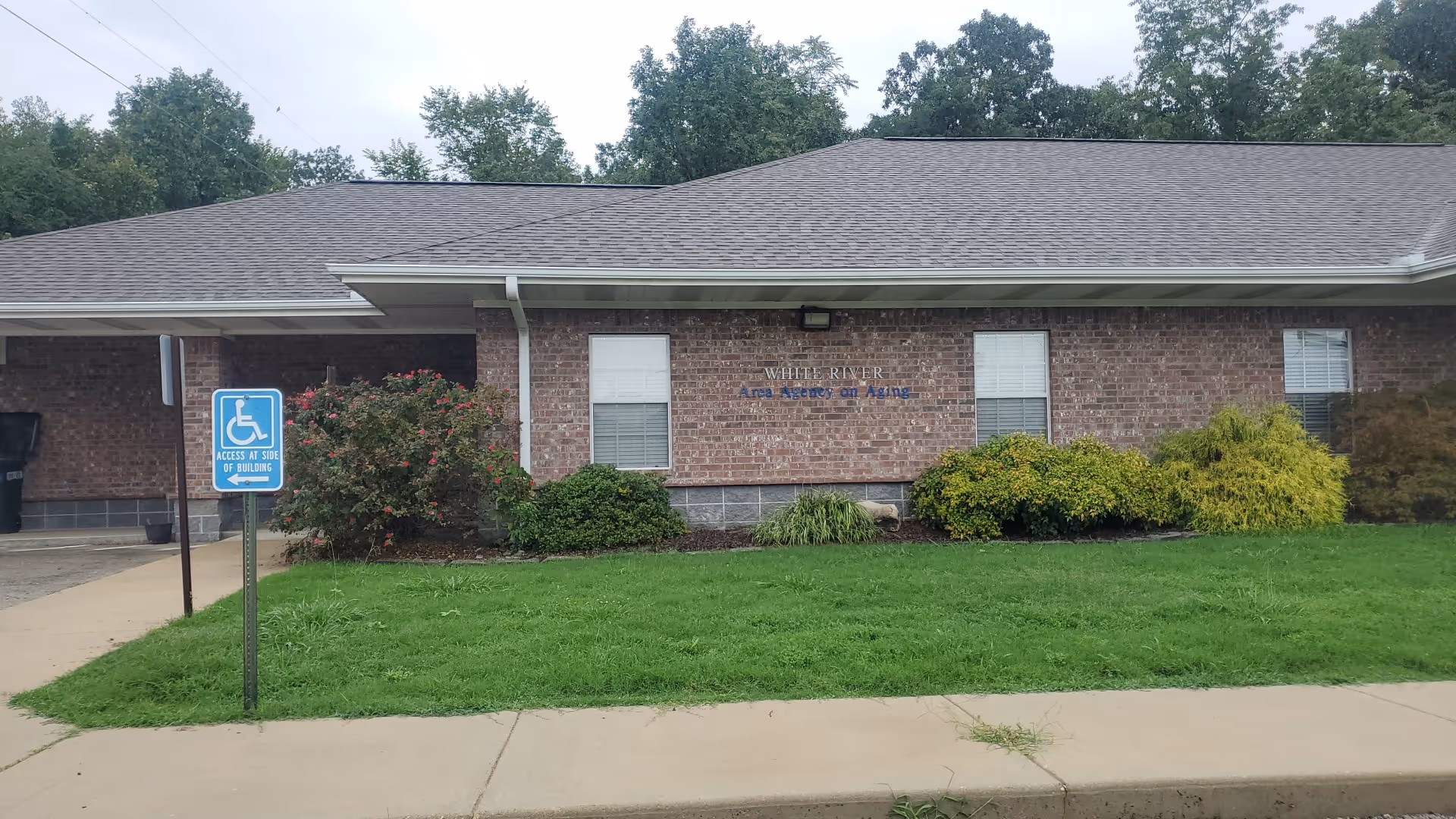 Brick facility with White River Area Agency on Aging sign, wheelchair accessible space, and landscaping.