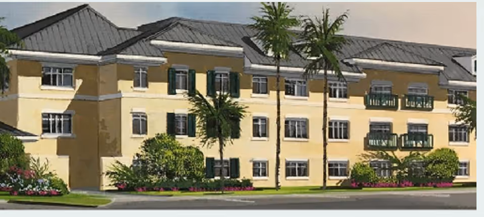 Yellow senior living building with green shutters, balconies, and palm trees.