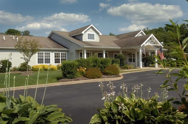 Front view of Freedom Residence senior living facility with a driveway and landscaped entrance.