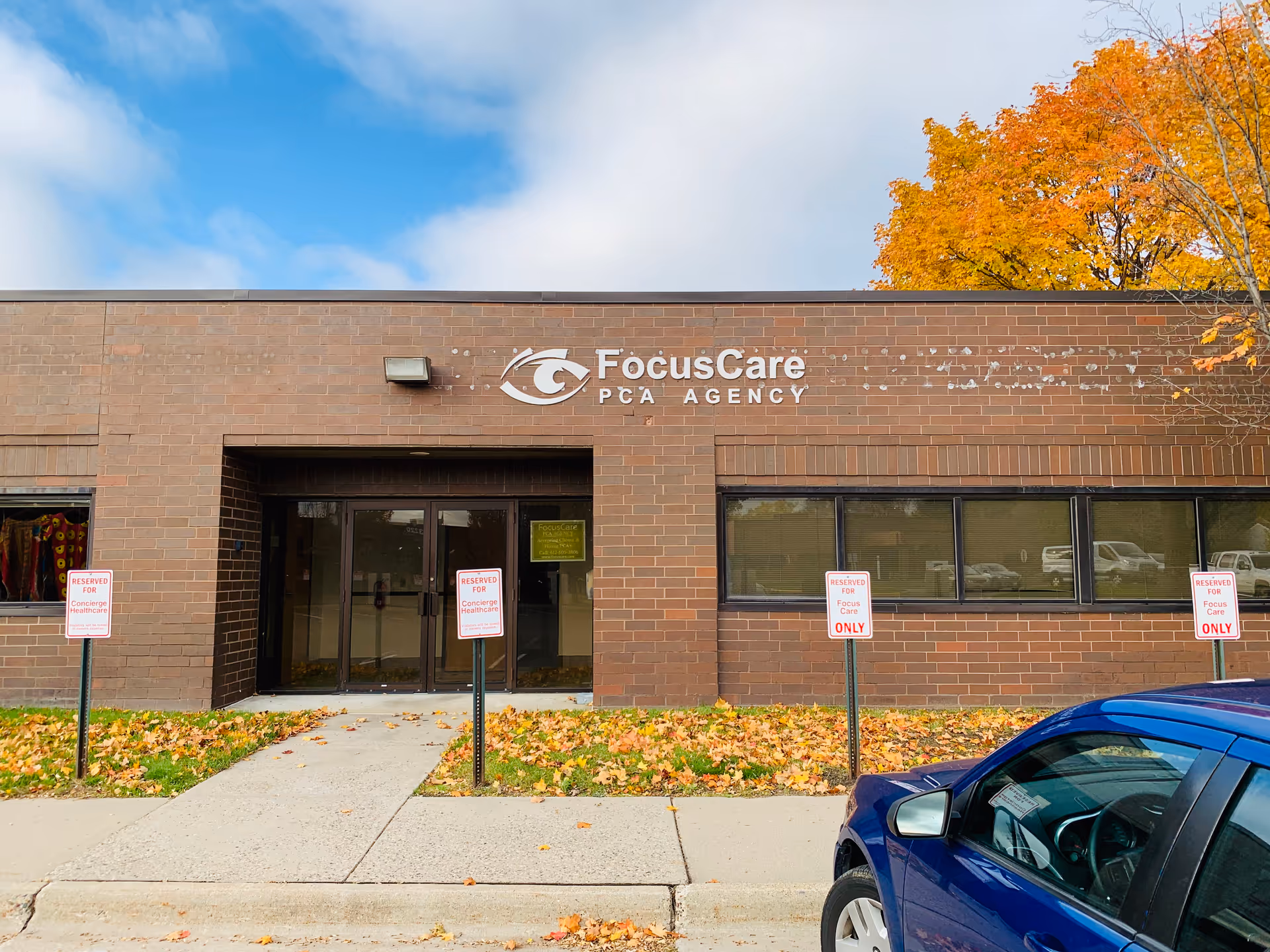 Brick building with FocusCare PCA Agency sign, front entrance, and a blue car outside.