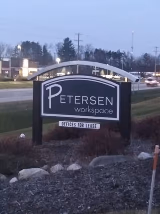 Outdoor building-front sign for Petersen workspace advertising offices for lease.