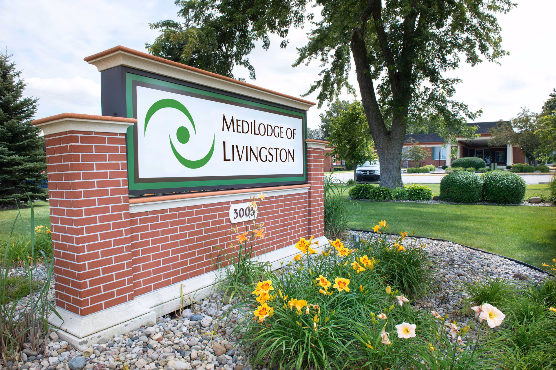 Brick sign for Medilodge of Livingston with landscaping and a building in the background
