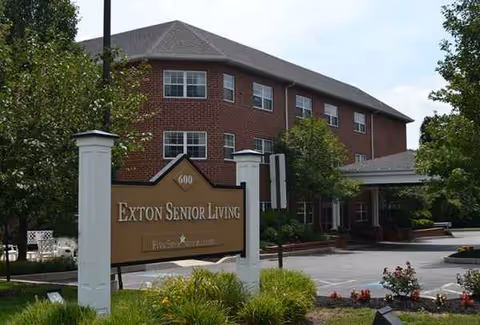 Exterior view of Exton Senior Living building with sign and landscaping.