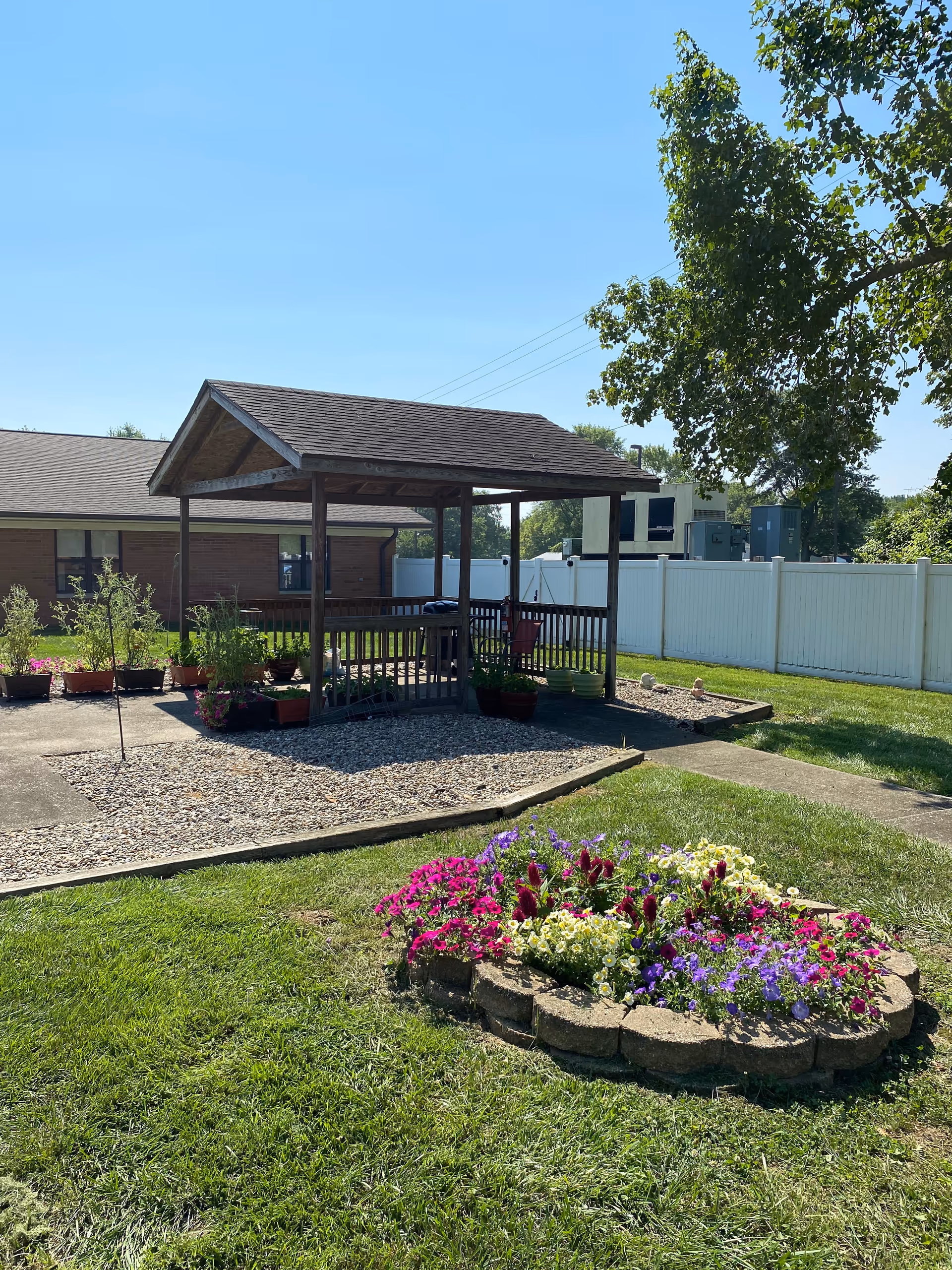 Outdoor garden area at Golden LivingCenter featuring a wooden gazebo and colorful flowers.