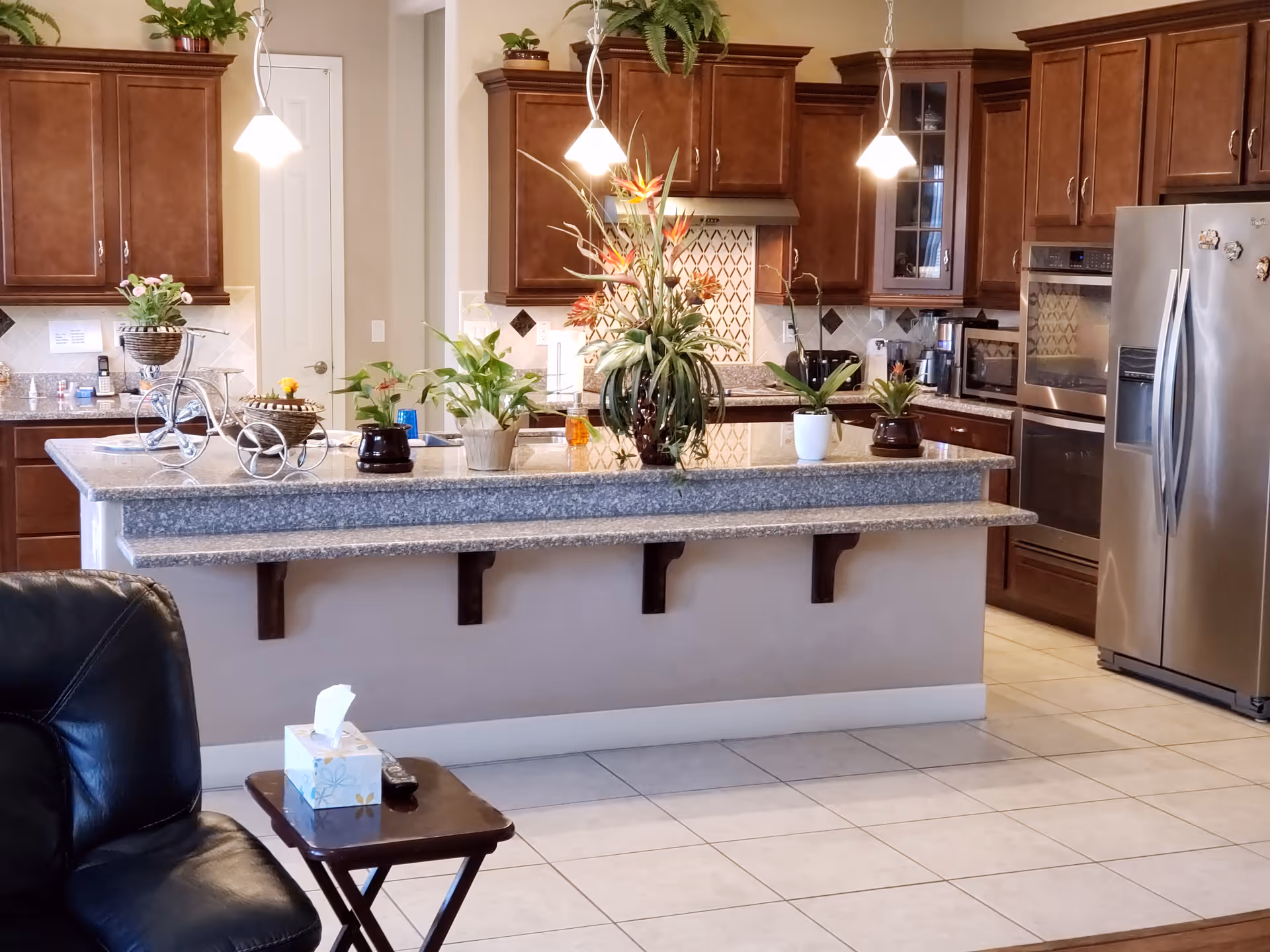 Modern kitchen with granite island, pendant lights, and stainless appliances in a dormitory.