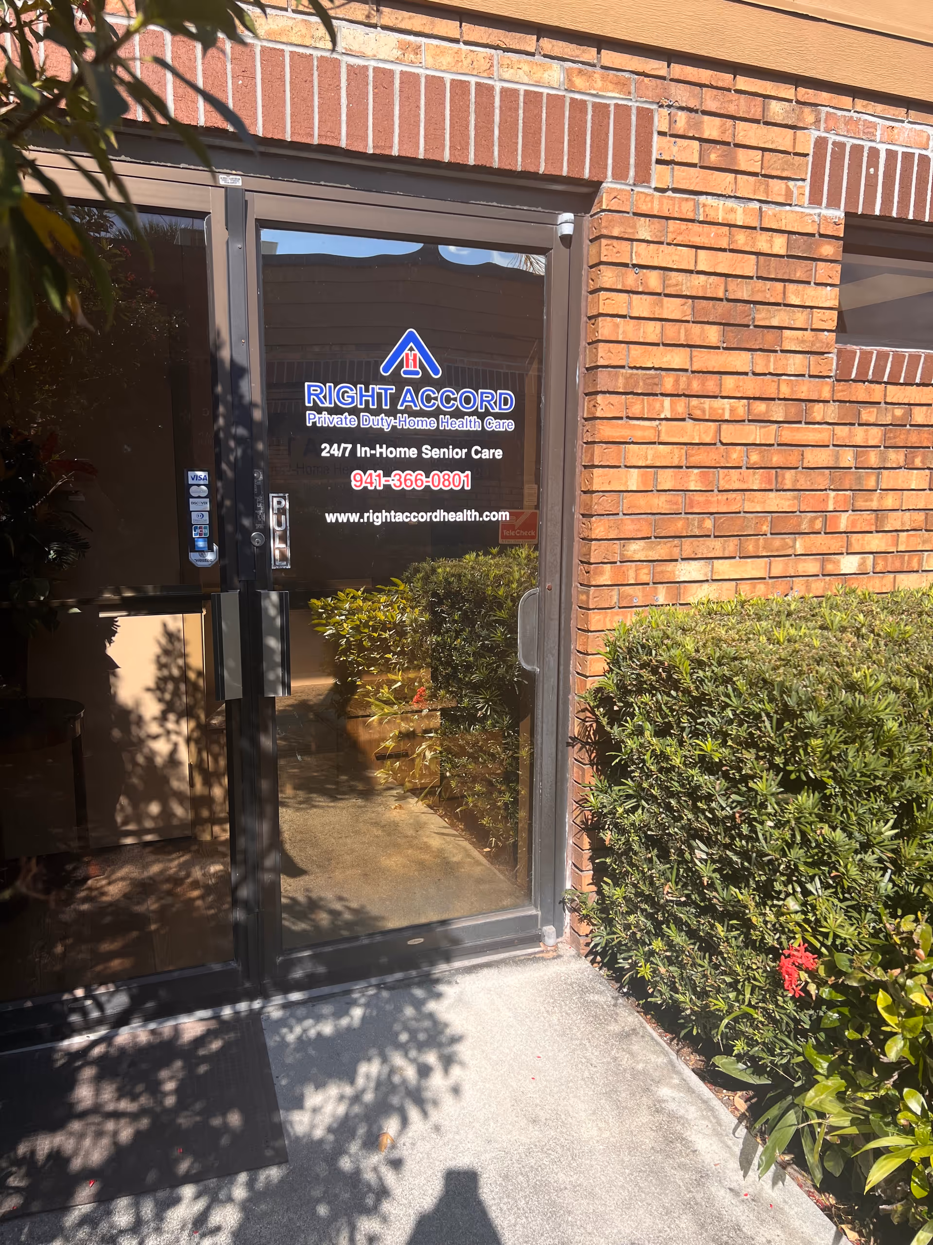 Glass entrance door for RIGHT ACCORD Home Health Care Venice on a brick building with greenery.