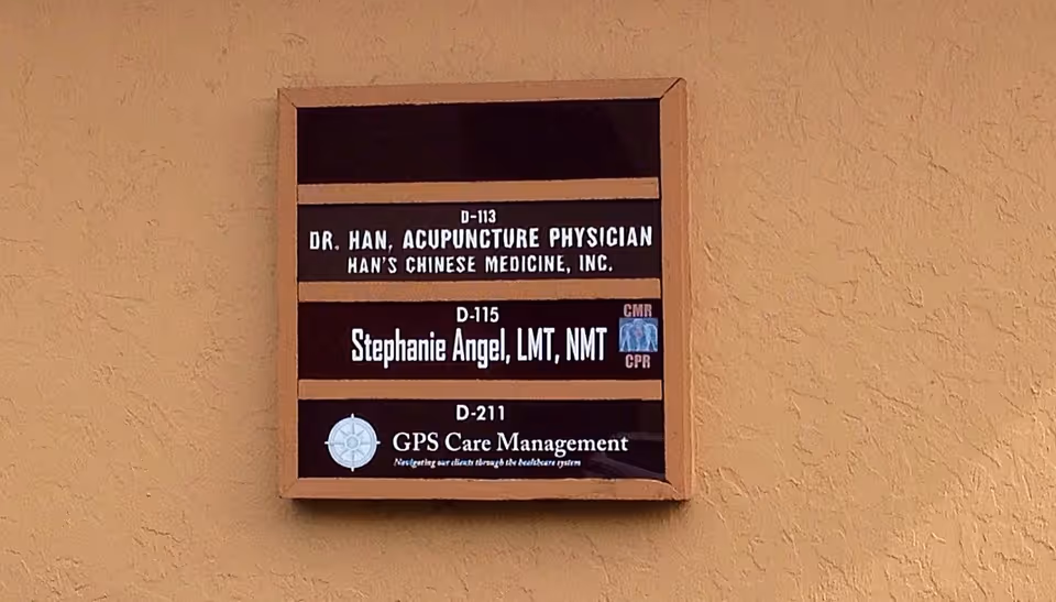 Wood-framed signboard on beige exterior wall listing GPS Care Management