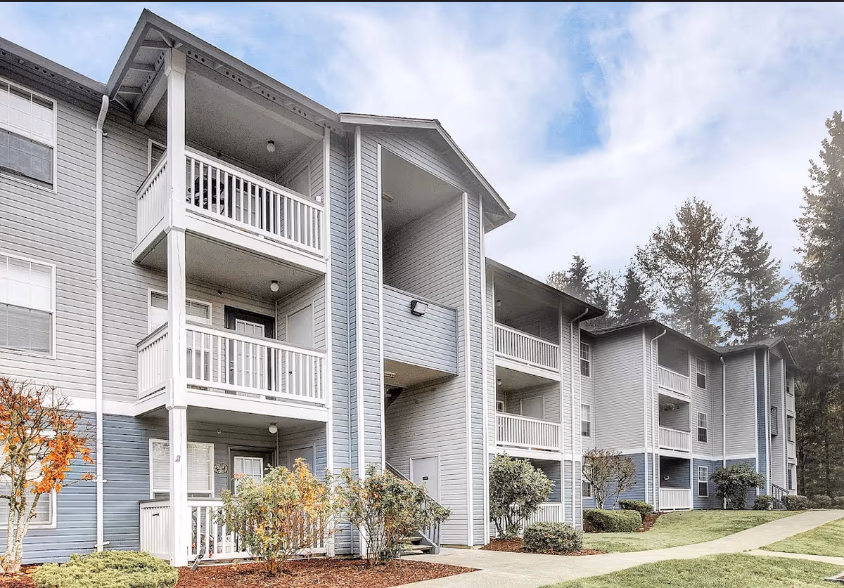 Exterior view of a multi-story senior living building with balconies and landscaped grounds.