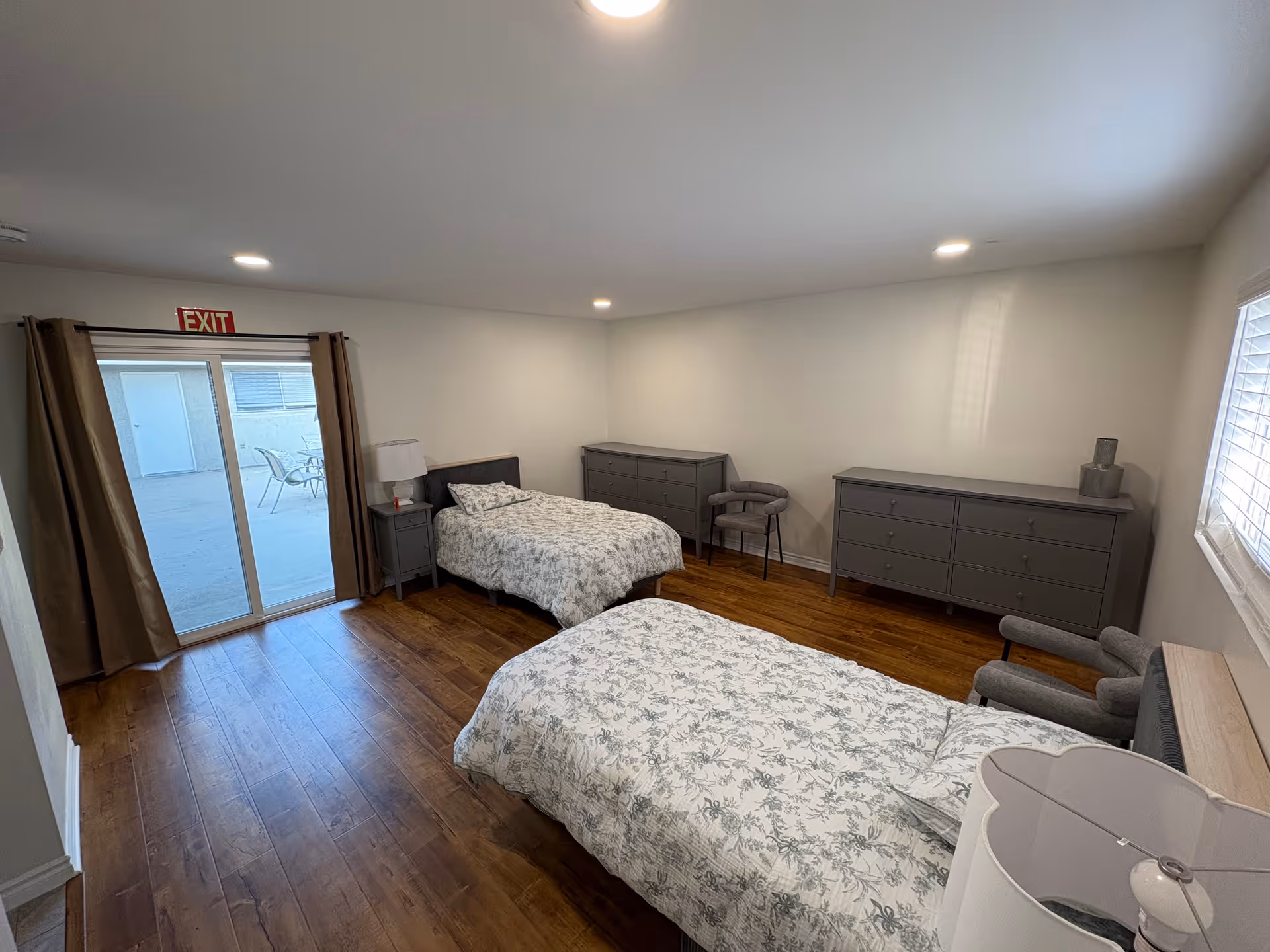 Two twin beds with floral bedding, dressers, and a sliding door to an outdoor patio.