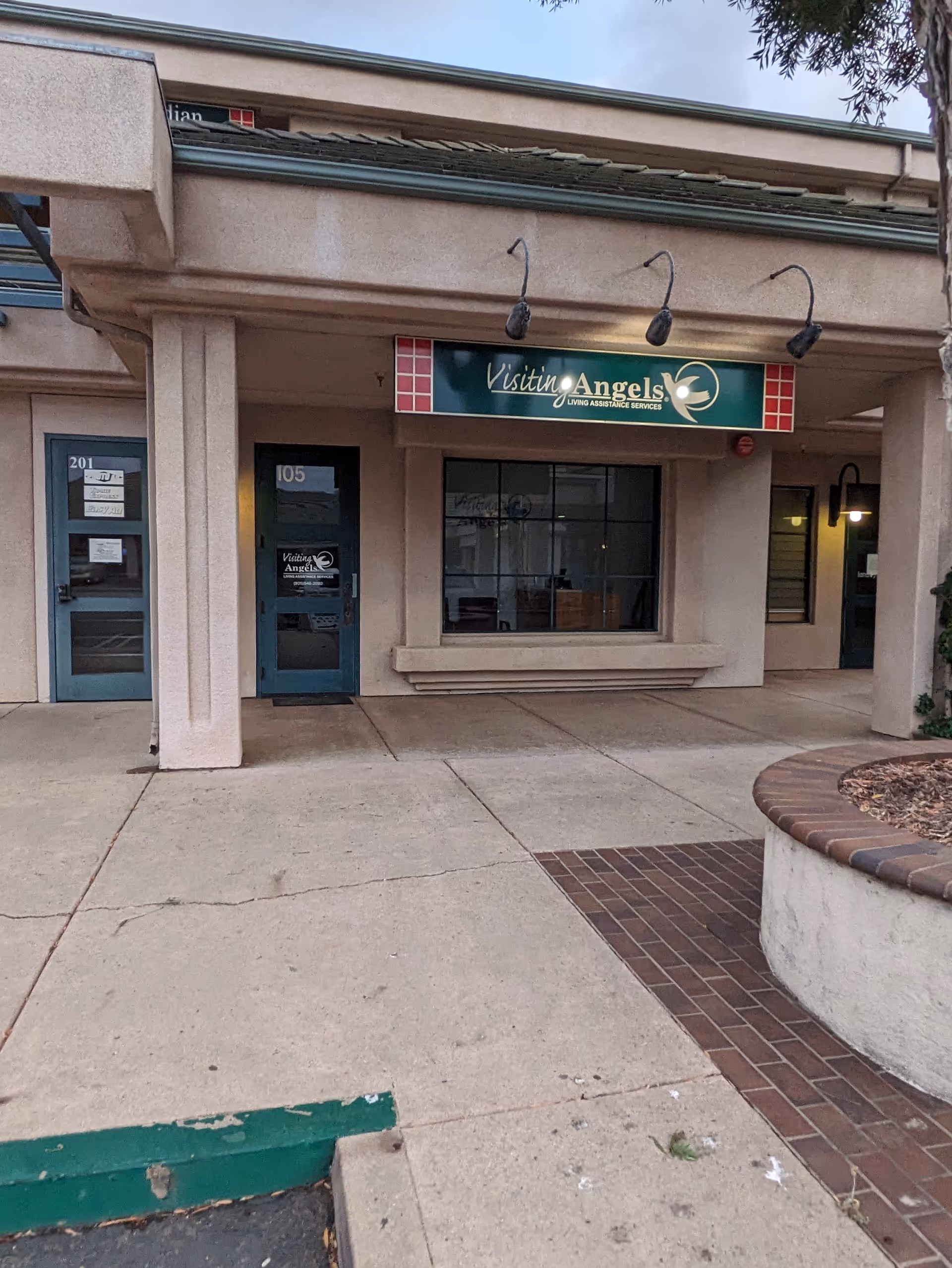 Exterior storefront of Visiting Angels with blue doors and a green sign.