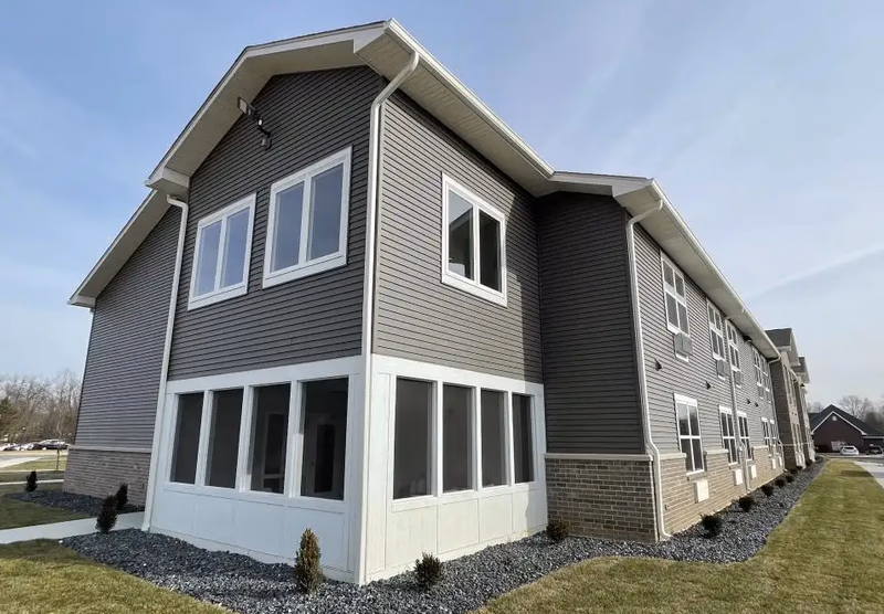 Exterior view of Autumn Trace Bedford Assisted Living building with gray siding and white trim.