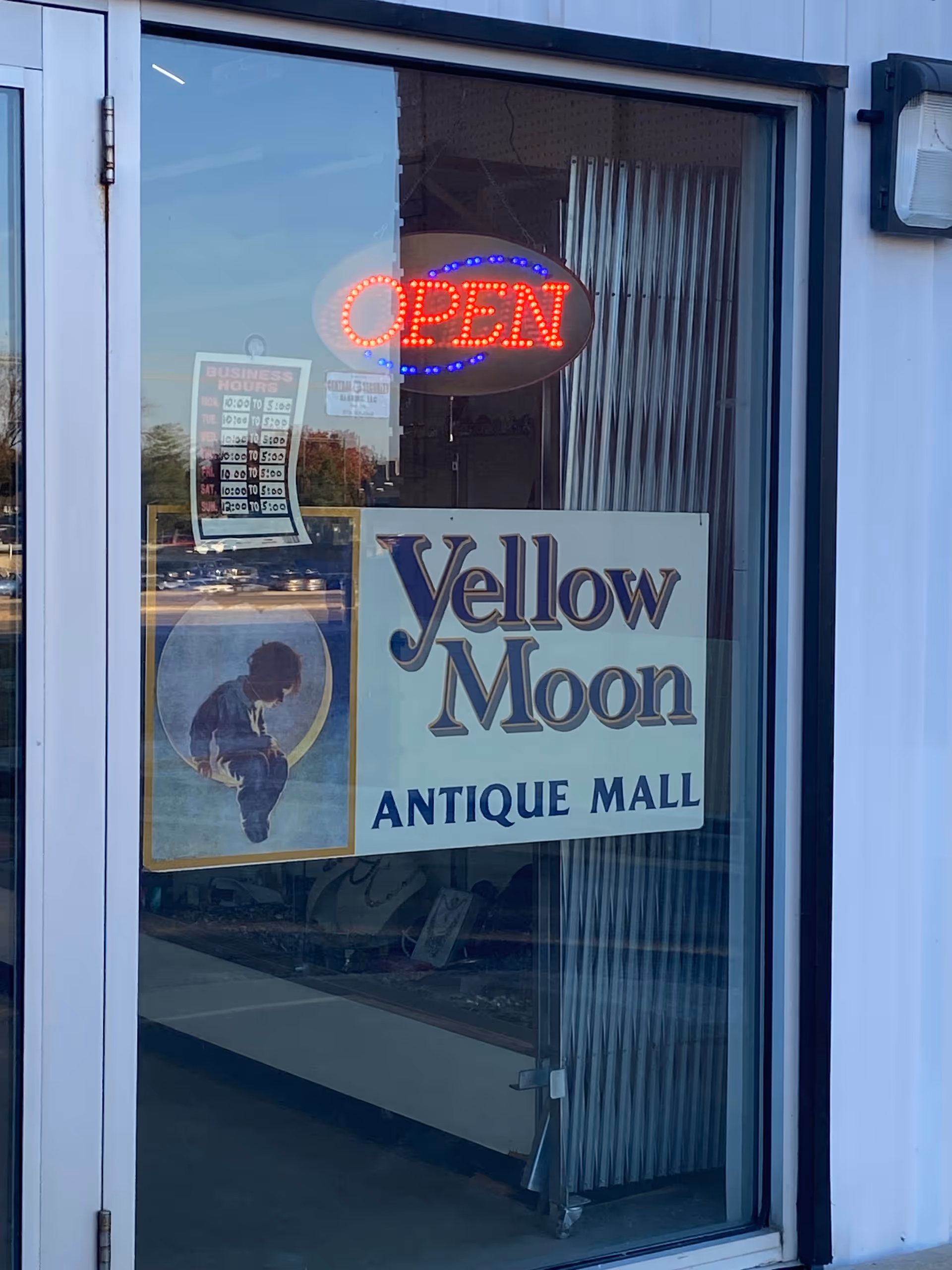 Storefront window with a neon OPEN sign and Yellow Moon Antique Mall signage.