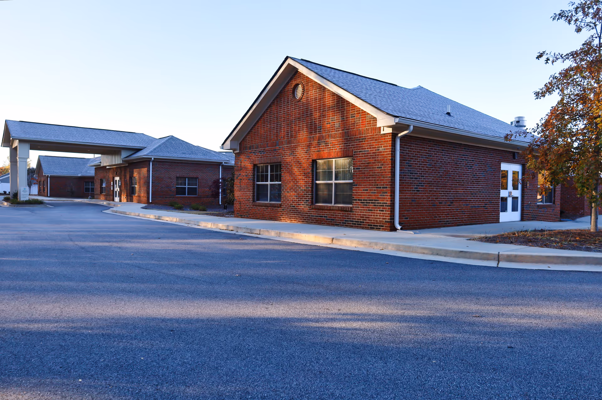 Brick hospice campus exterior with connected buildings and a curved driveway.