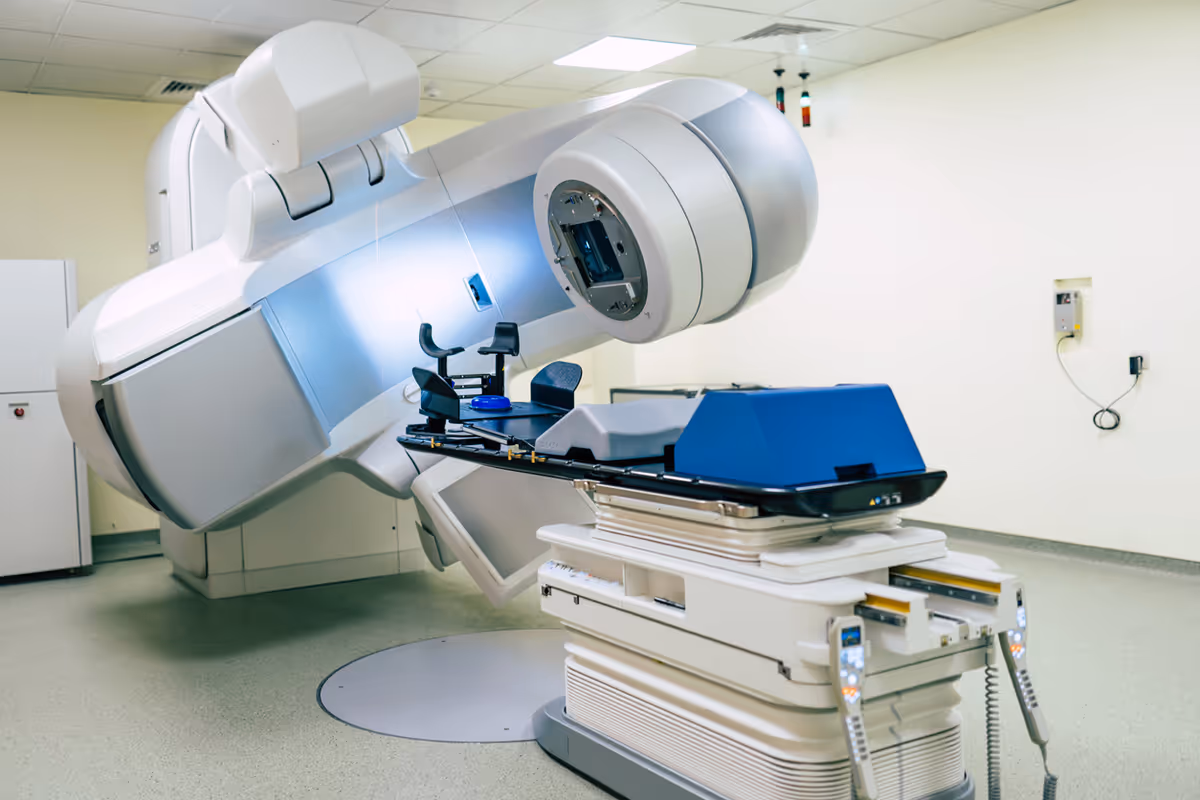 Large medical radiation therapy machine dominates a clean, modern treatment room.