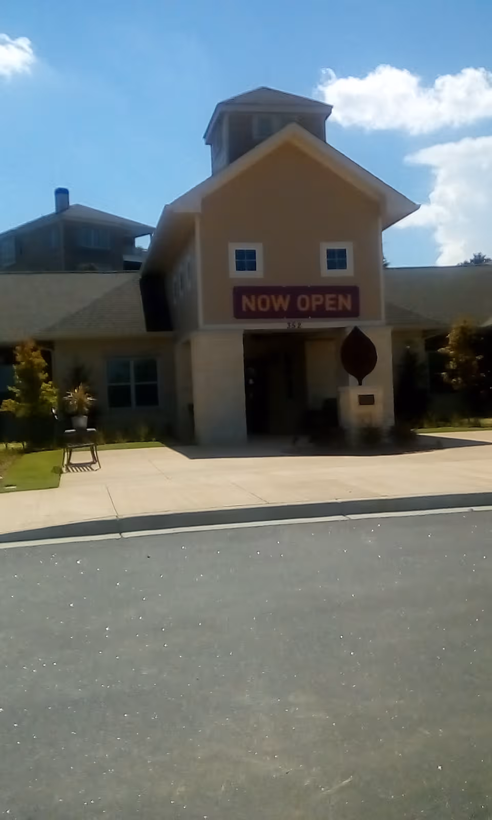 Front exterior of a senior living facility with a 'NOW OPEN' sign over the entrance.