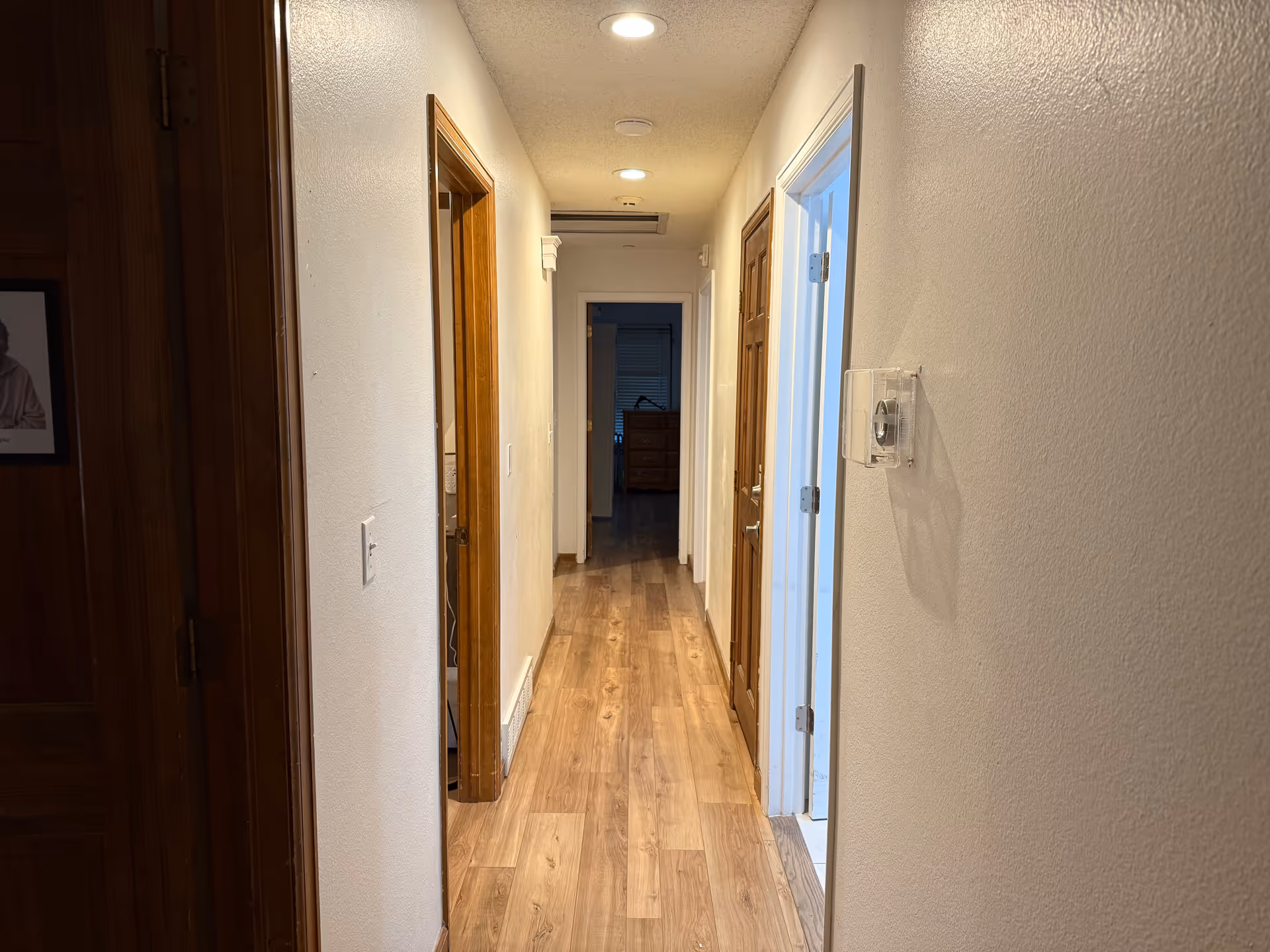 Narrow residential hallway in a senior care facility with wood doors and warm lighting.