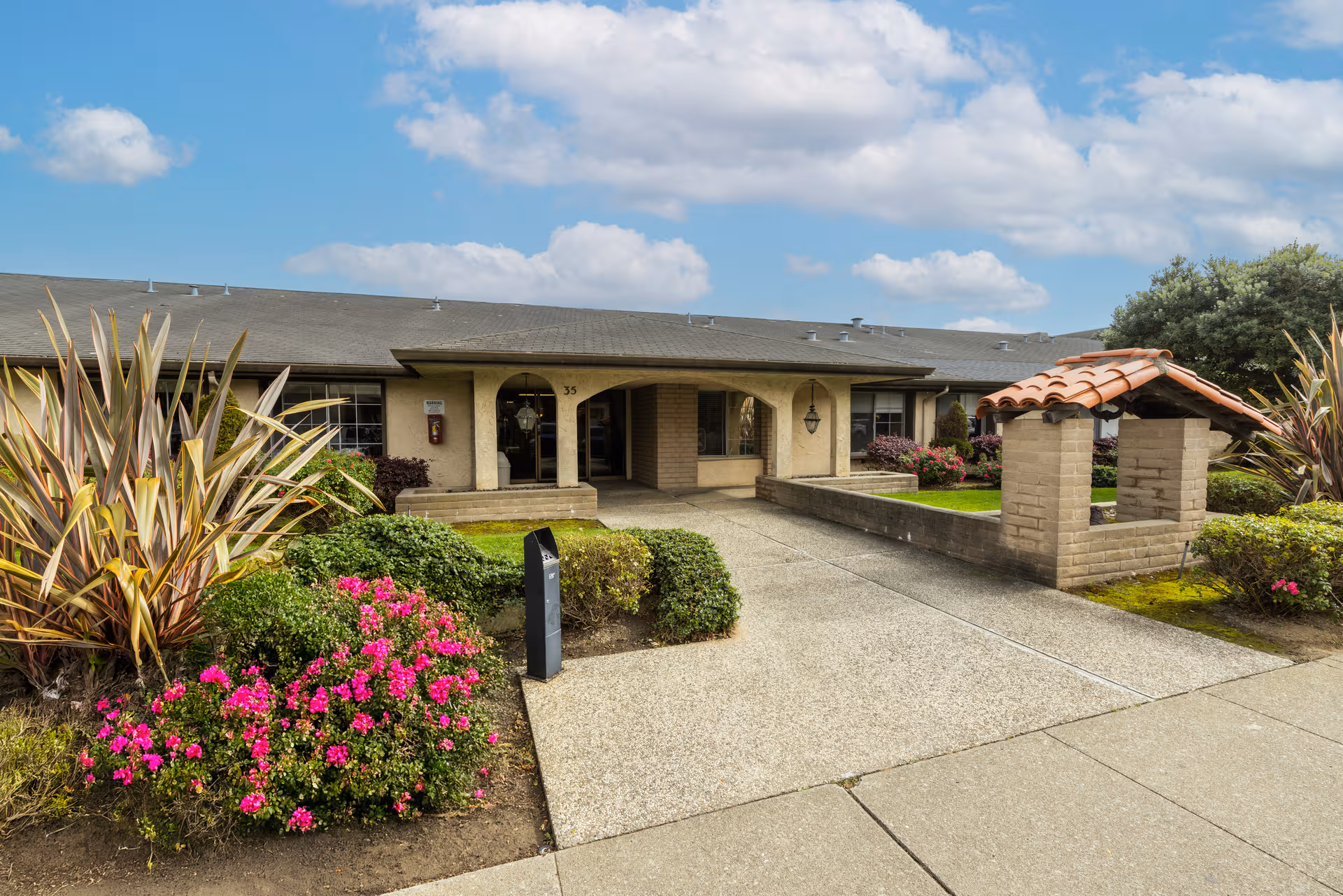 Front entrance of a senior living facility with landscaped walkway and brick portico.