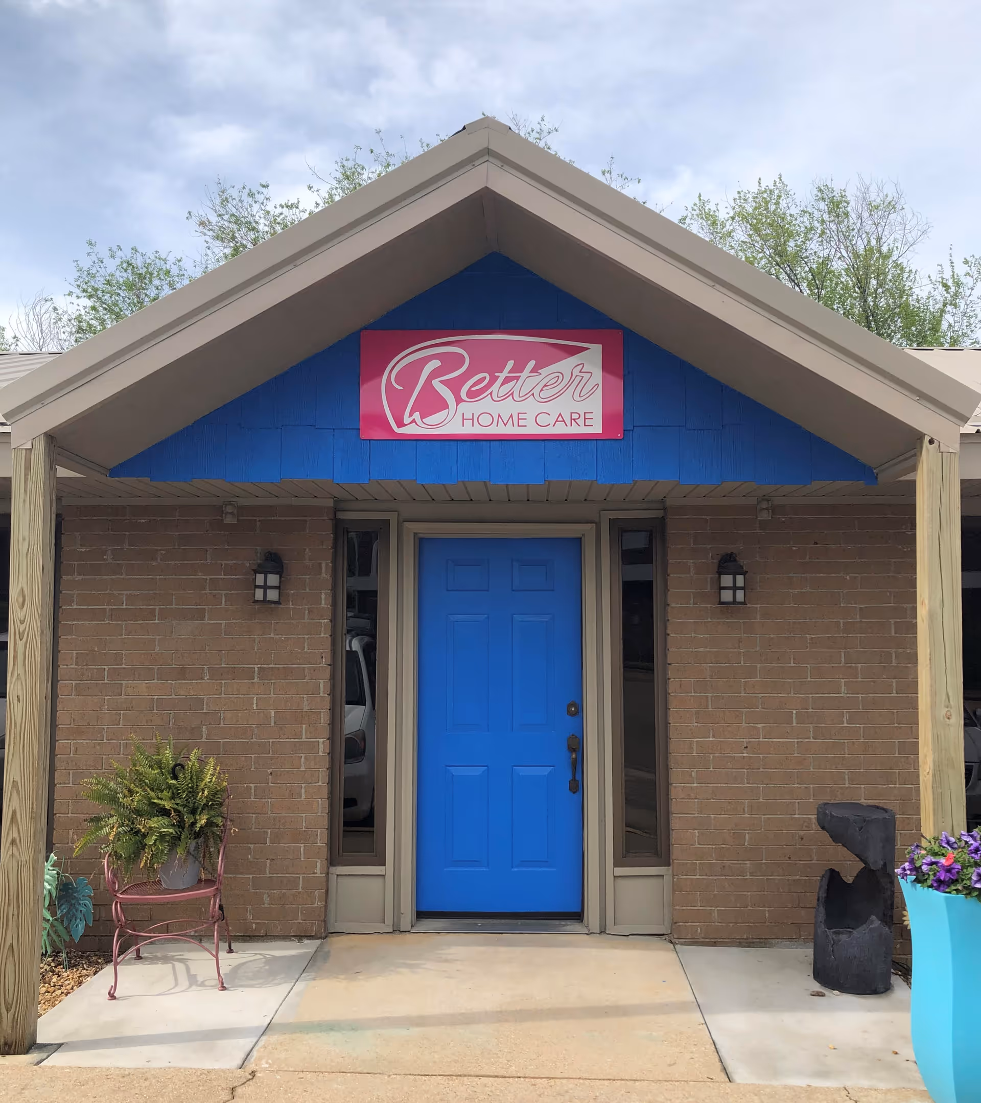 Front entrance of Better Home Care facility with a bright blue door and pink sign.