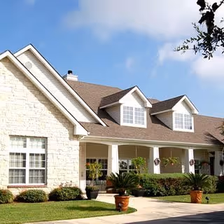 Stone siding and beige exterior of a senior living facility with a covered front porch.