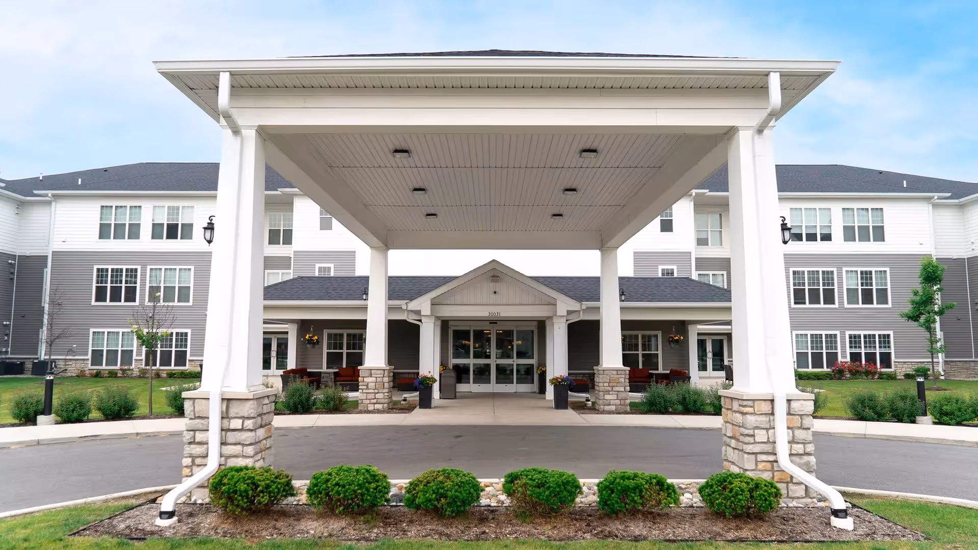 Exterior view of a senior living facility with a covered entrance and landscaped front.