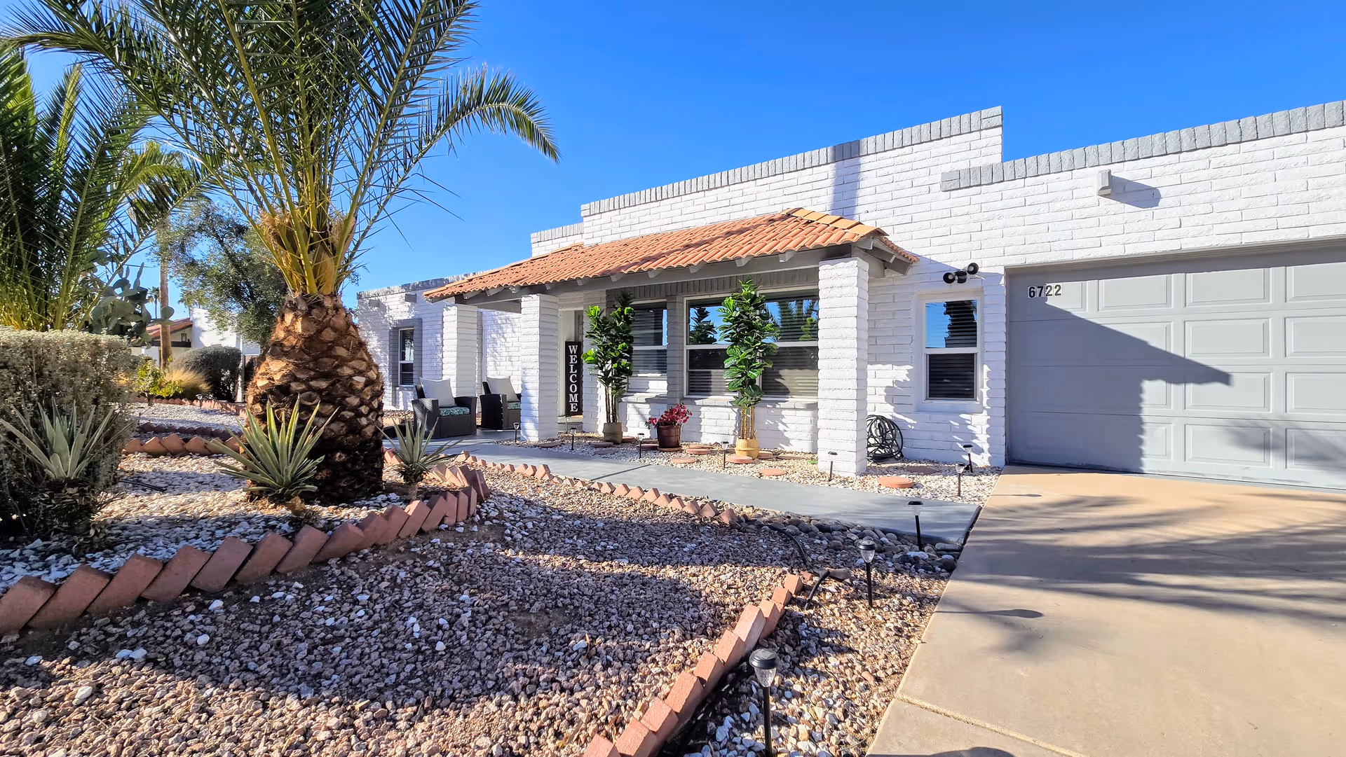 A white, single-story senior living facility exterior with palm trees and desert landscaping.