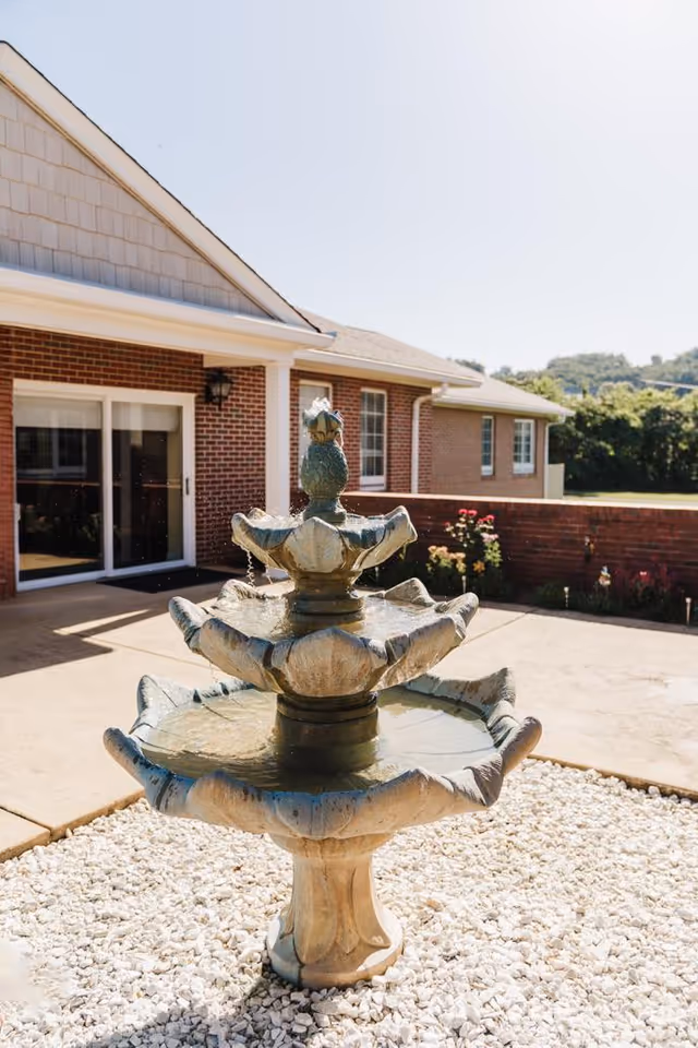 Outdoor fountain in front of a brick senior living center.