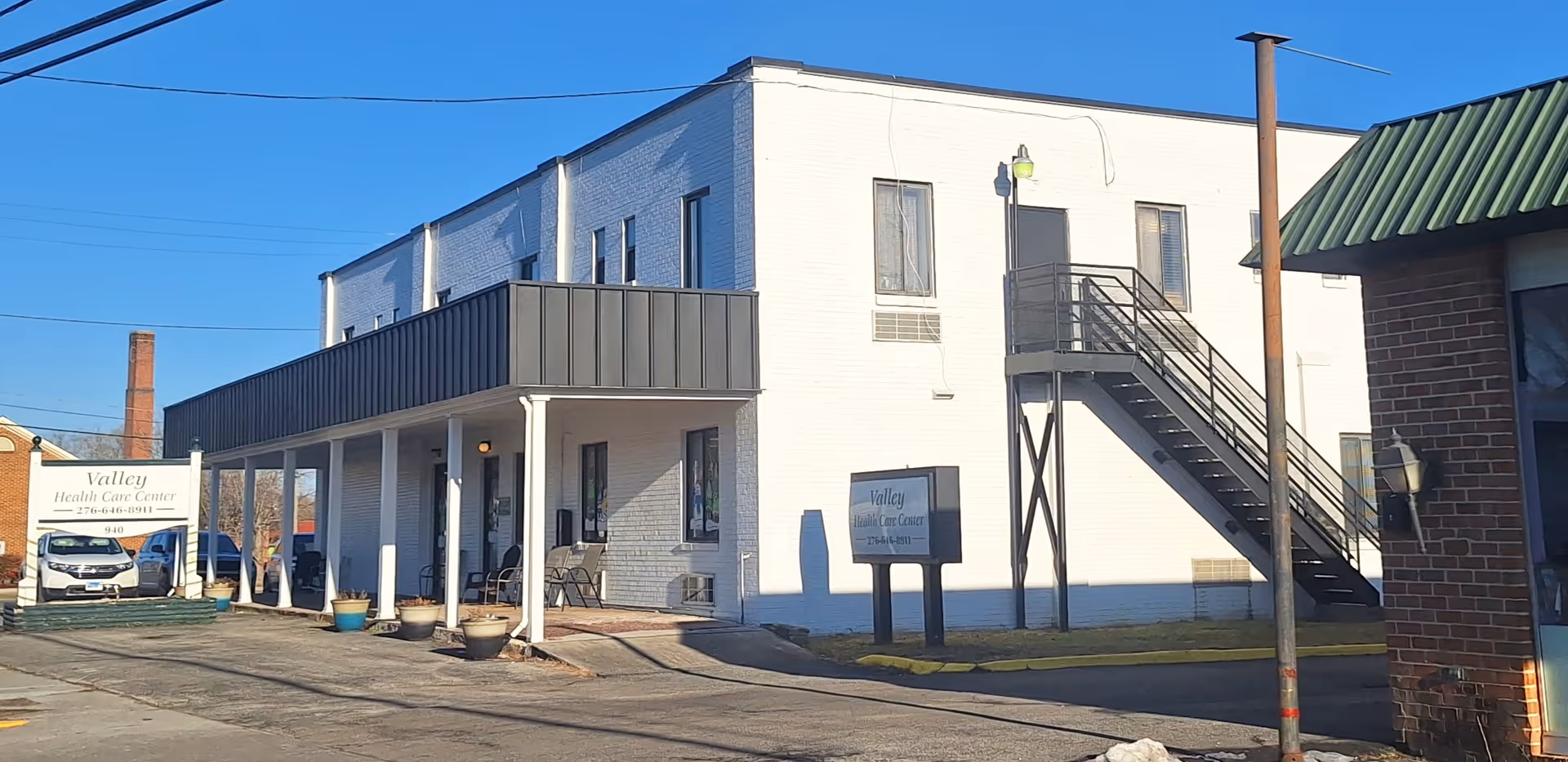 Exterior of Care One-Valley Healthcare Center: white two-story building with an external staircase.