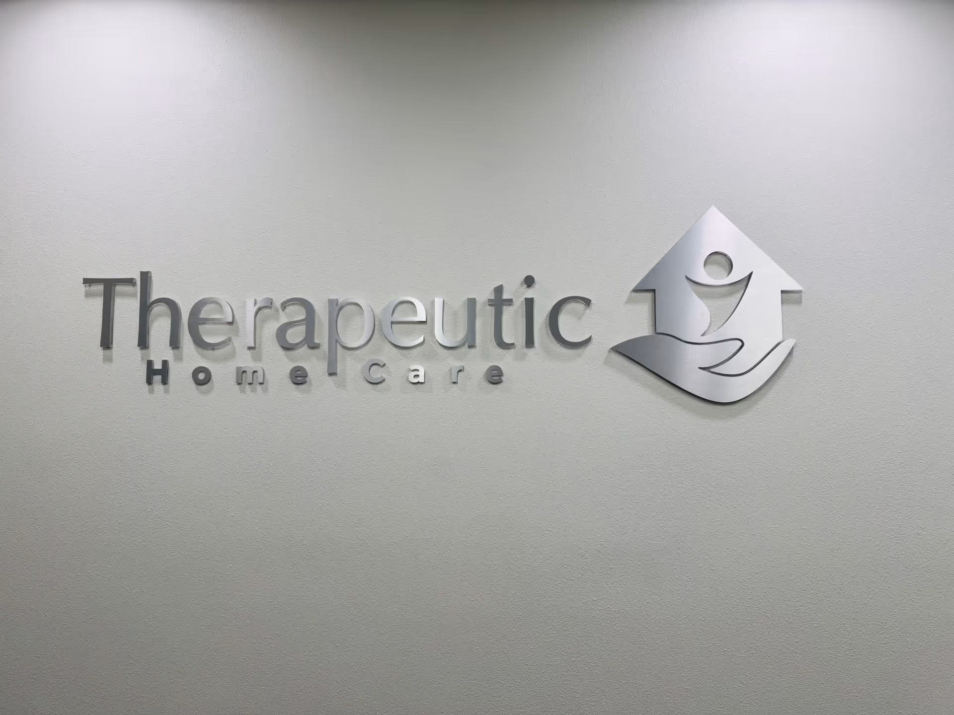 Indoor wall with a raised Therapeutic Home Care logo plaque.