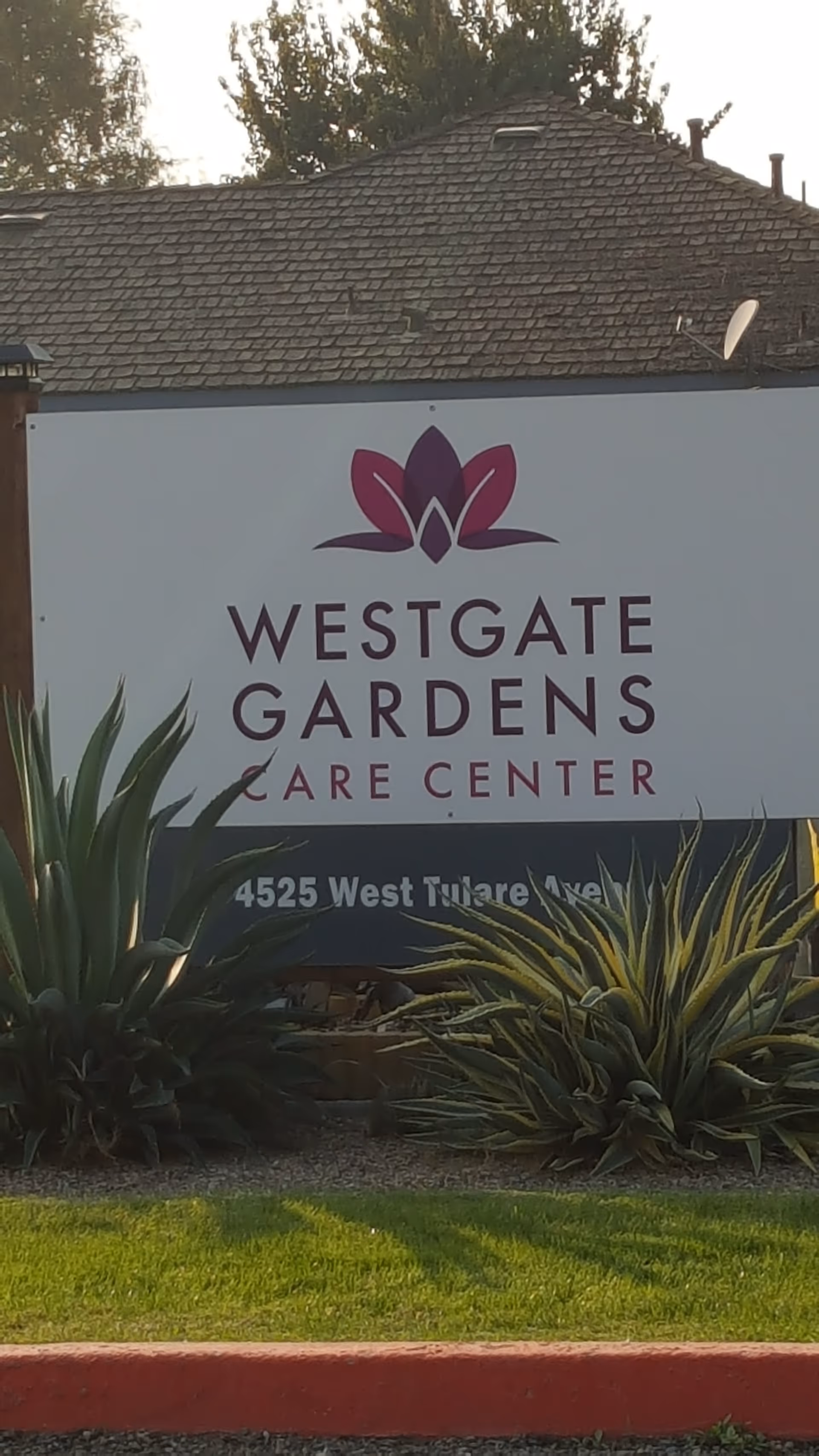 Sign reading Westgate Gardens Care Center on a building exterior with surrounding plants.
