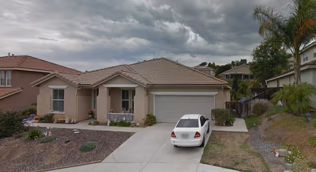 Front exterior of a single-story beige facility with a garage and parked white car.